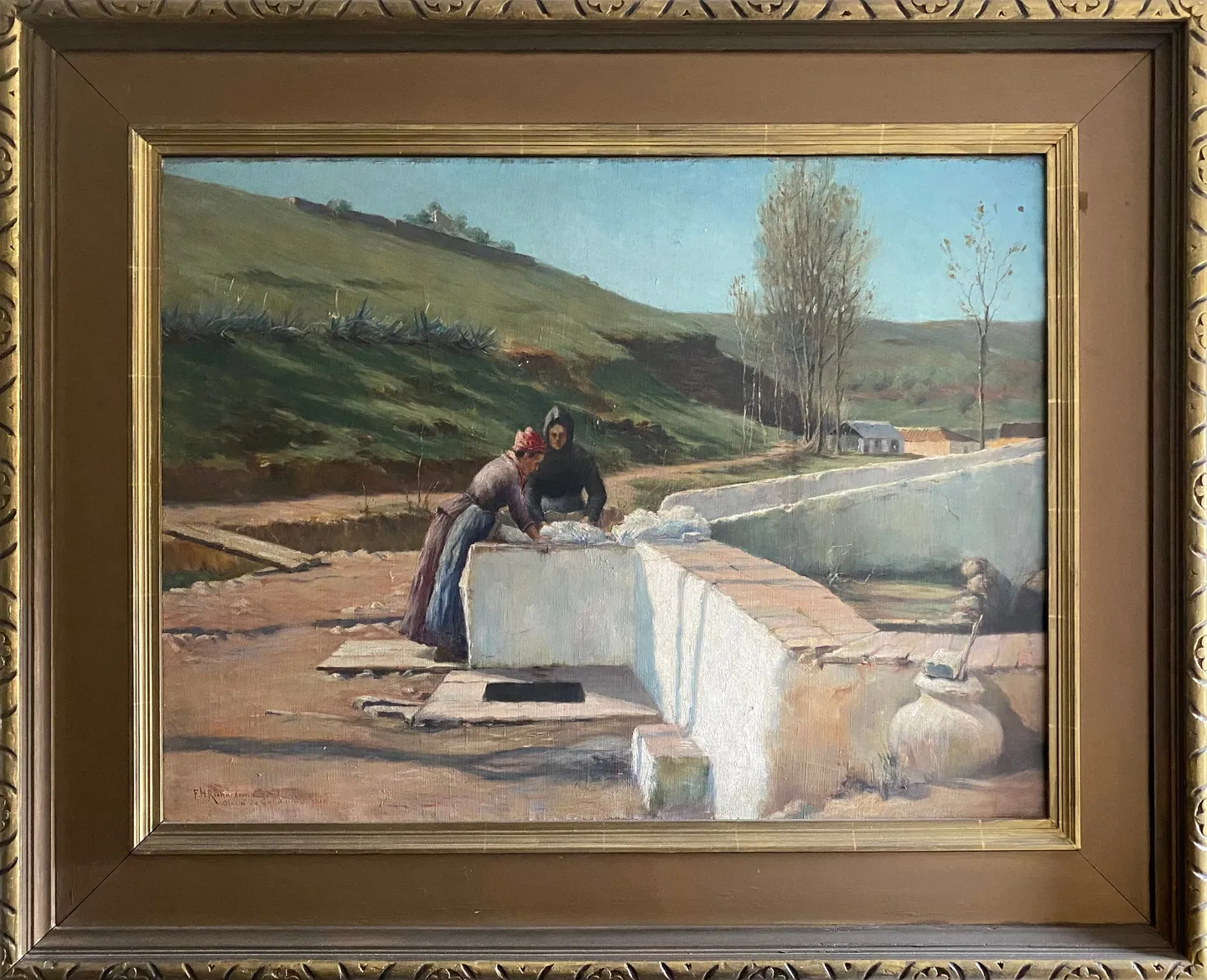 Two women at a stone washing trough in a sunny hillside village