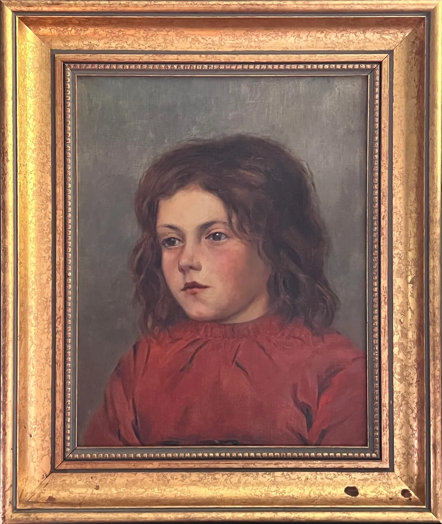 A young child with long brown hair in a red smock