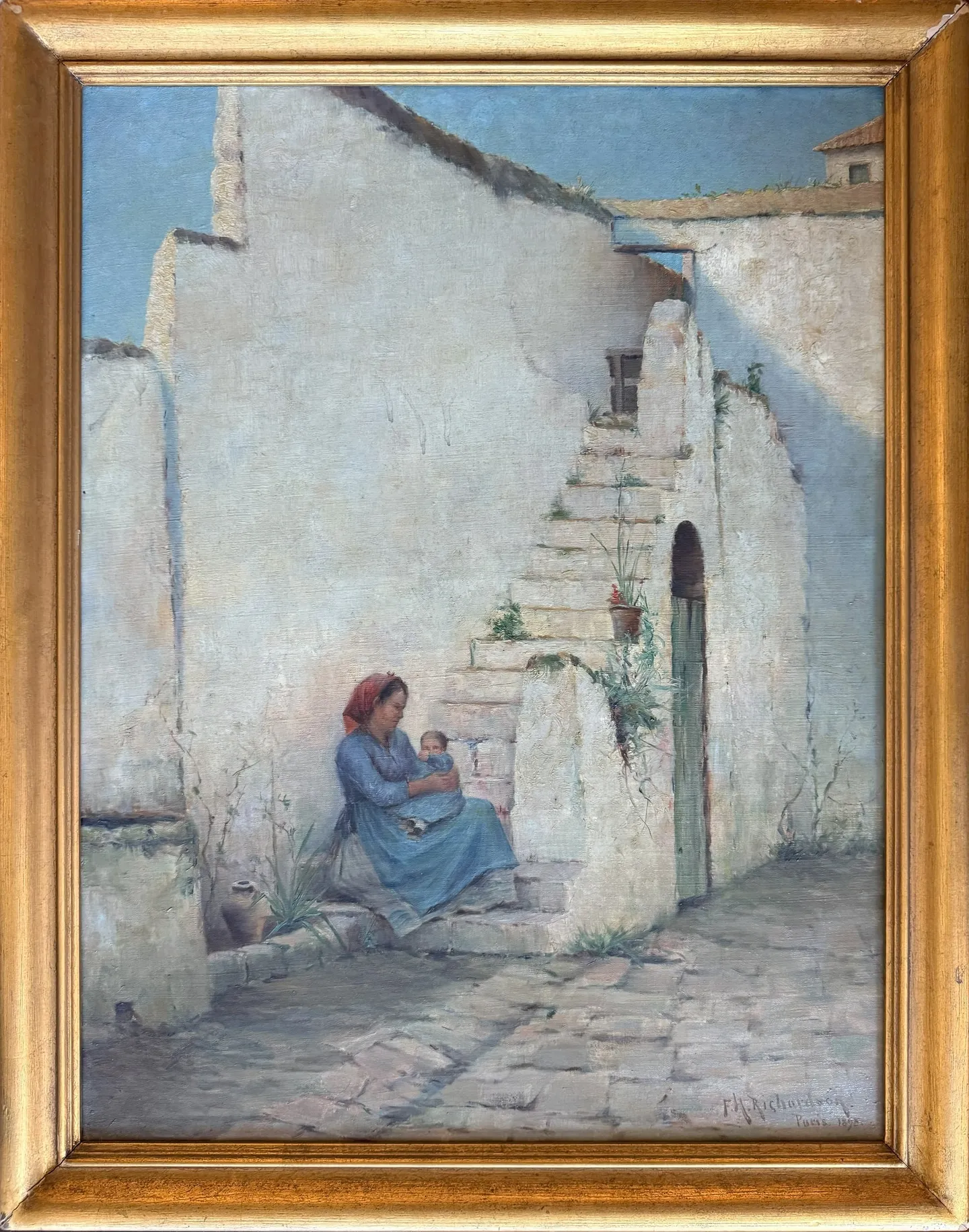 A woman holding a child at the foot of whitewashed stairs in a sunlit patio