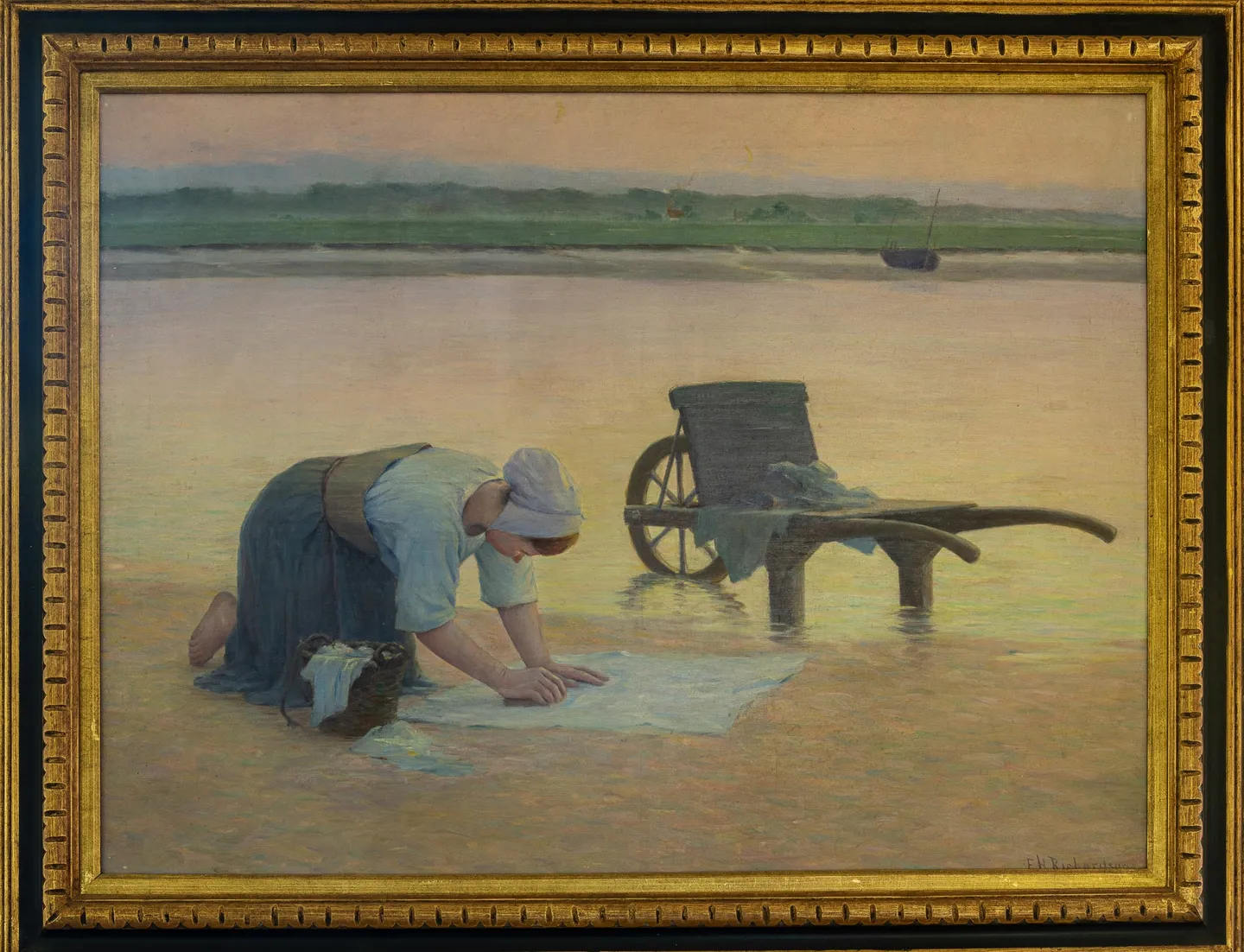 A woman kneels on wet sand at sunset beside a two-wheeled cart