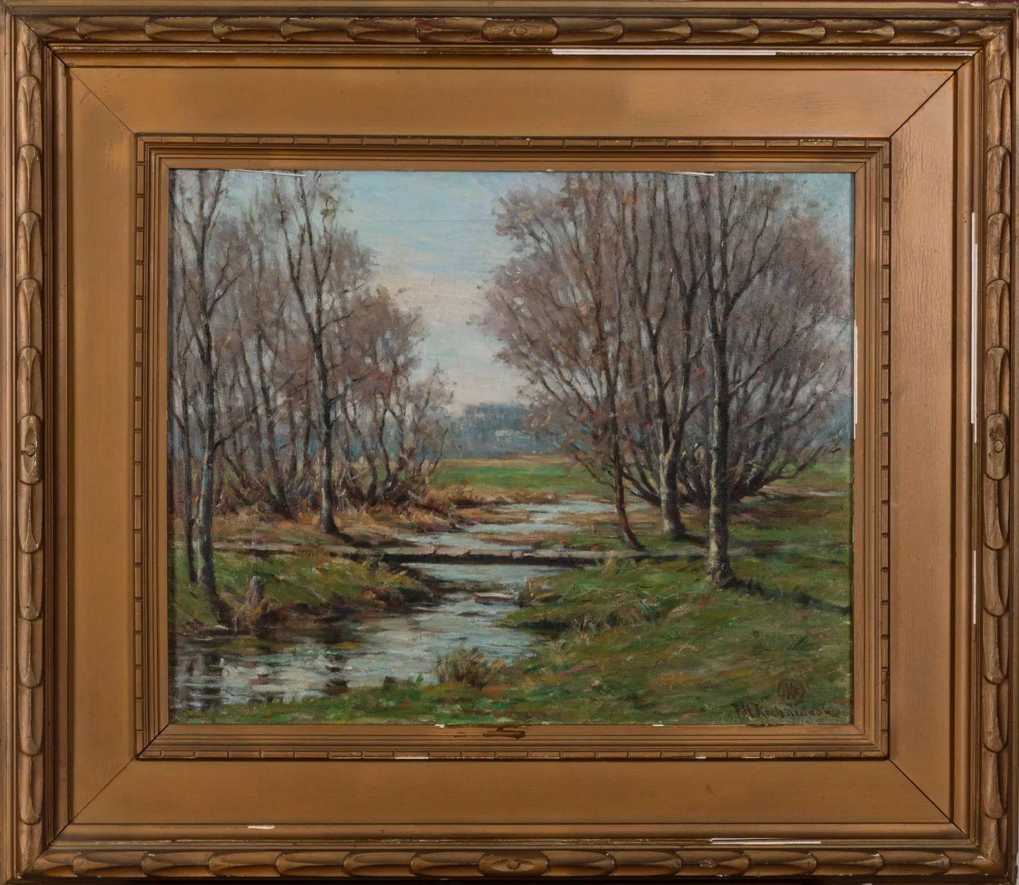 A stream winding through a meadow between slender autumn trees