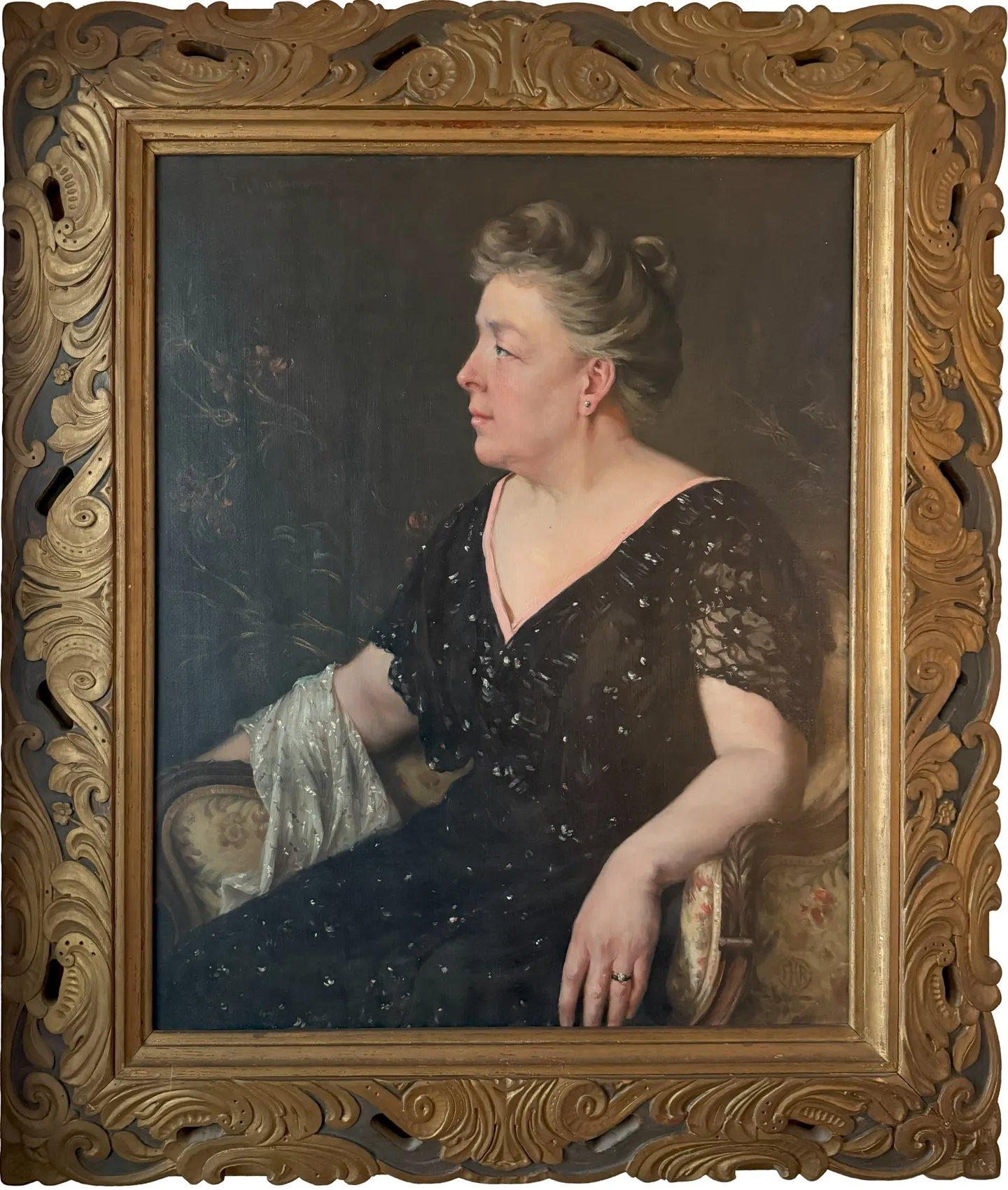A seated woman in a black beaded gown, seen in profile