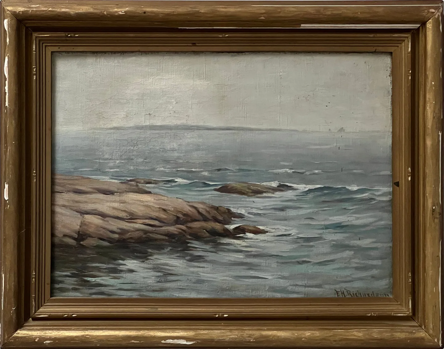 Grey sea washing over a low rocky shore under an overcast sky