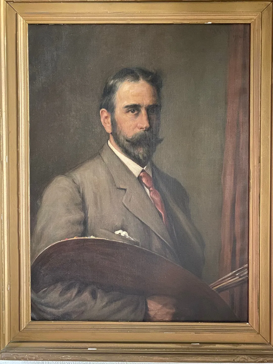 The bearded artist in a grey suit, holding his palette and brushes