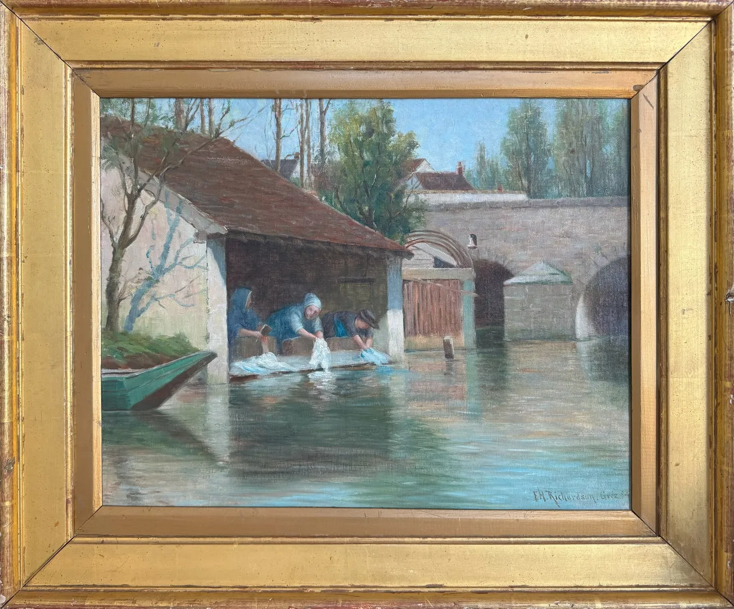 Women washing linen at a riverside washhouse beside a stone bridge