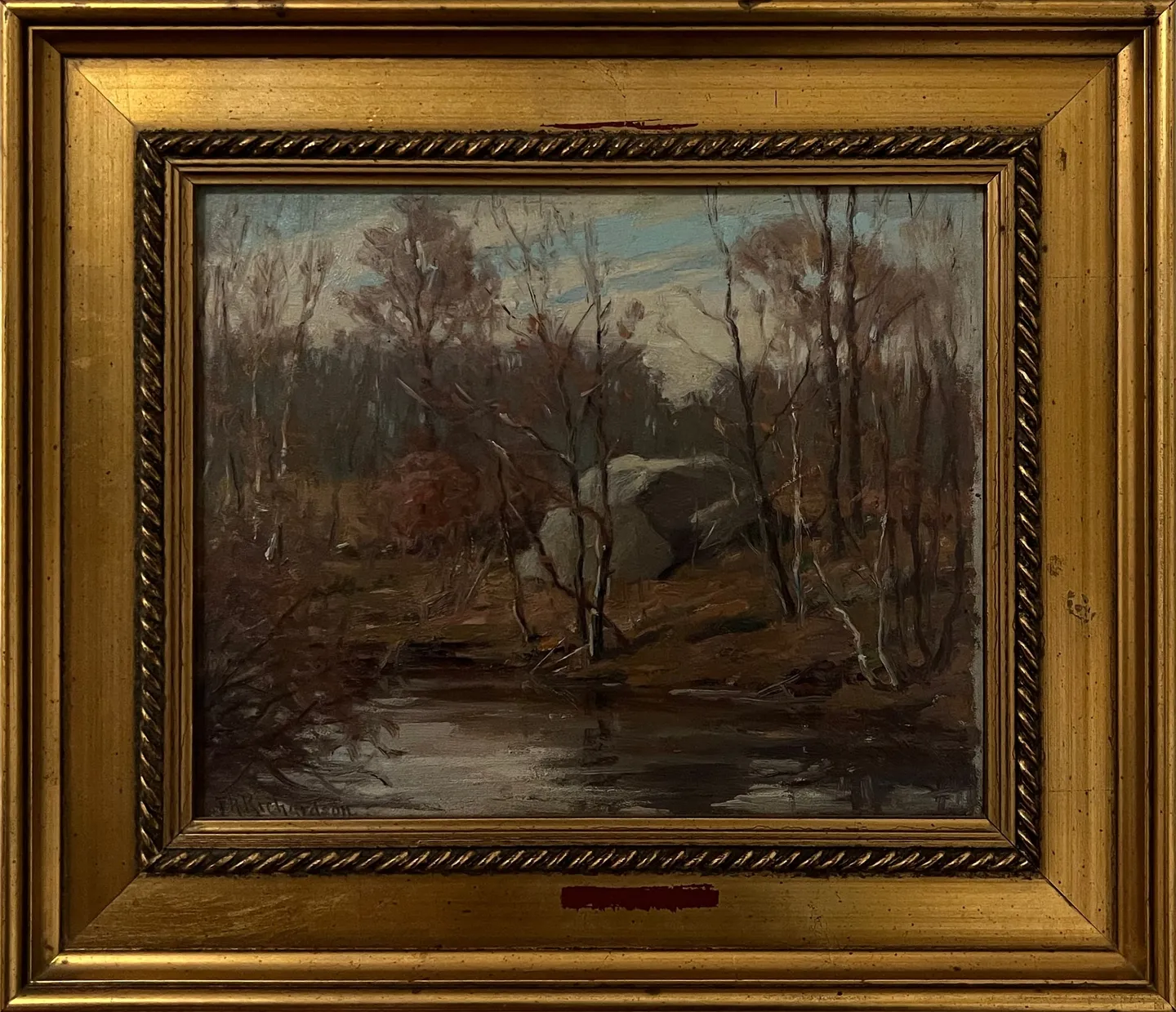 Bare trees and boulders reflected in a dark woodland pond